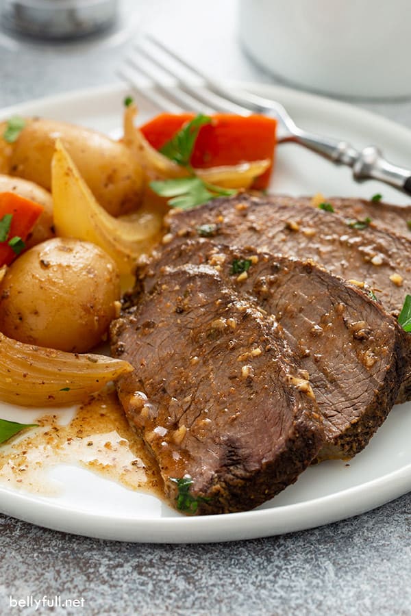 sliced pot roast with gravy on white plate