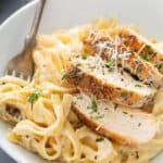 close up of chicken alfredo on white plate