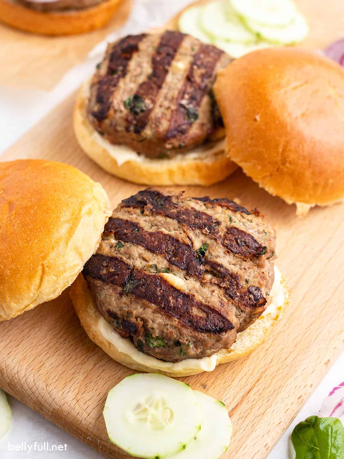 grilled burger on bun sitting on cutting board