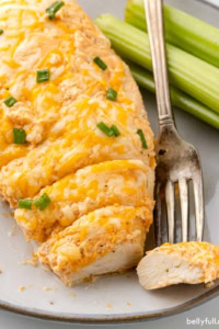 A baked buffalo chicken breast with one bite on a fork
