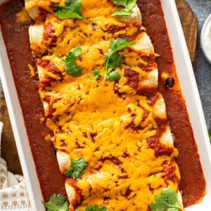 chicken enchiladas covered in melted cheddar cheese in baking dish