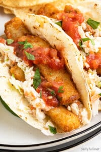 close up fish stick tacos with coleslaw and salsa on plate