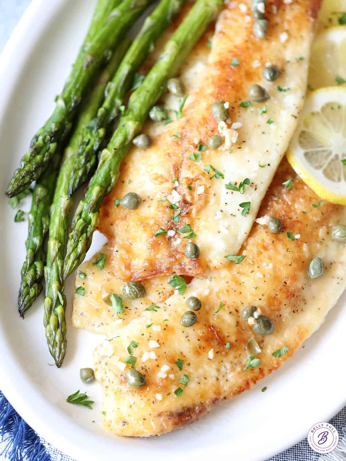 overhead fish piccata on plate with garlic and capers